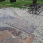 Installateur bevestigt aardingskabel aan een koperen aardpen in de tuin